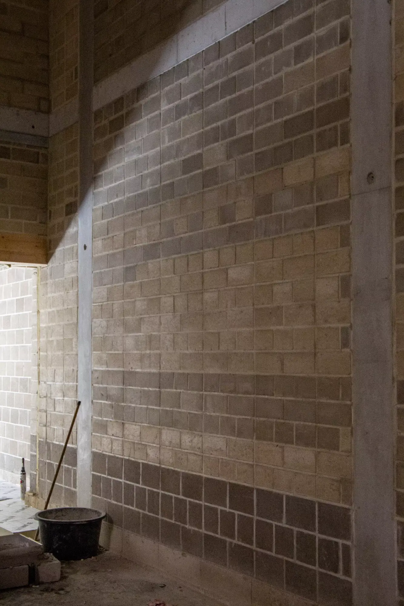 Projet Magasin 4 — mur intérieur fini en blocs de terre comprimée apparents. Légende du site : « Compressed earth block CEB - Blocs de terre compressé BTC - Perssteen »